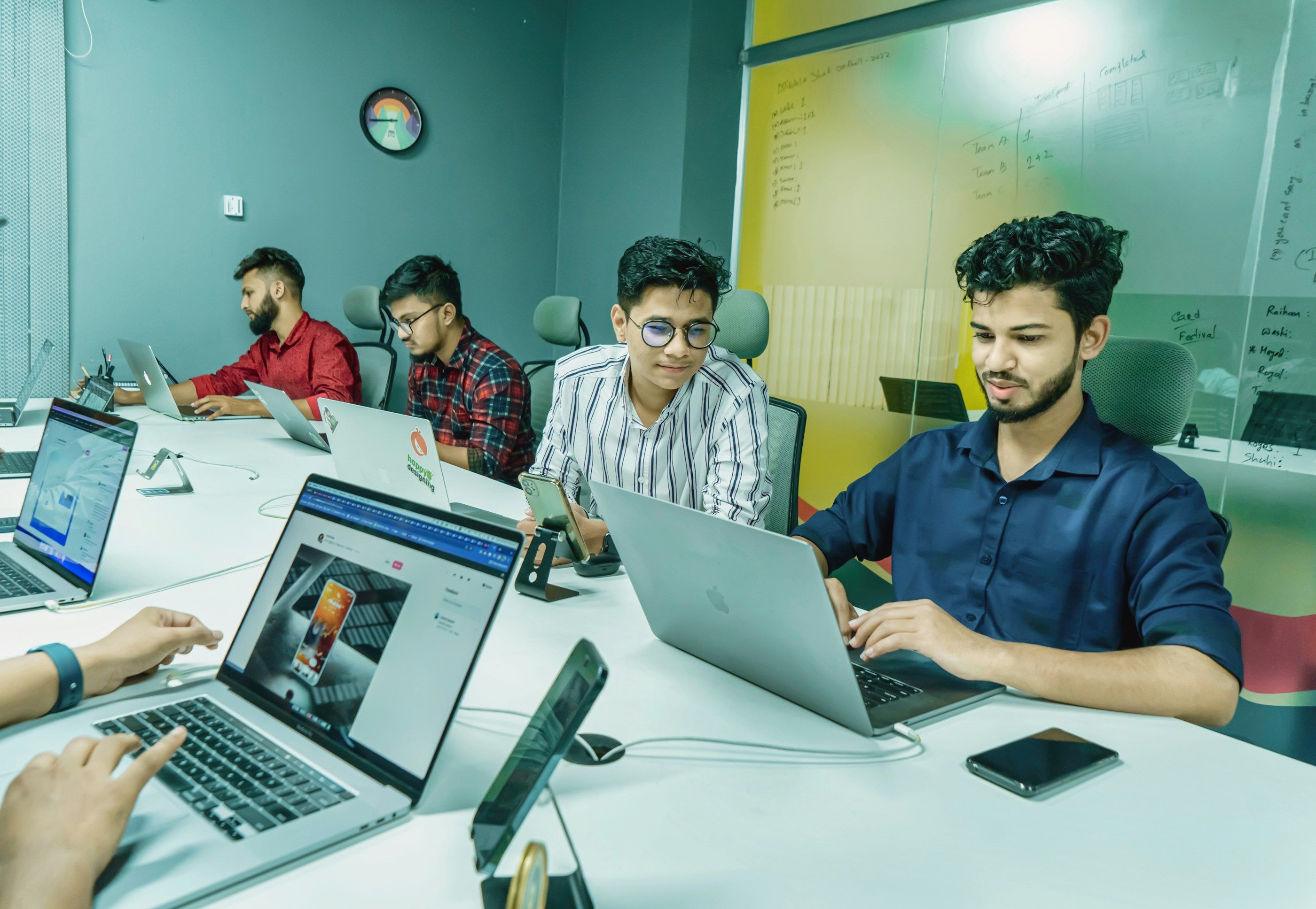 A team of developers coding together on laptops around a studio table